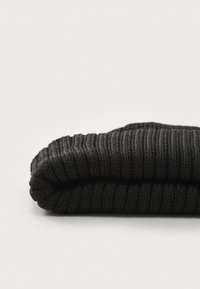 Zwarte gebreide beanie met een geribbelde textuur en een omgeslagen rand. Het materiaal is zacht en rekbaar, geschikt voor koud weer.