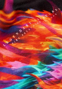 Mehrfarbiger Textilstoff mit lebhaften abstrakten Mustern in Rot, Orange, Pink und Blau, auf dem der Text "Legendäre Kreaturen" deutlich zu sehen ist.