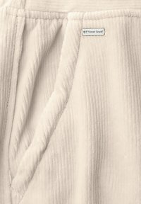 Tissu couleur crème avec une texture côtelée. Comprend une petite étiquette métallique avec "Street One". Design doux et léger avec des poches latérales.
