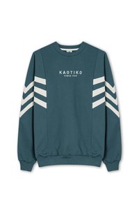Teal sweatshirt med hvide chevron-striber på ærmerne. Har en rund halsudskæring og ribbede manchetter. Forsiden viser "KAOTIKO" logoet og året for etableringen.