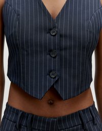 Marineblaues Nadelstreifen-Westen mit V-Ausschnitt-Design, ausgestattet mit drei schwarzen Knöpfen und einer verkürzten Passform. Das Material scheint glatt mit feiner Textur zu sein.