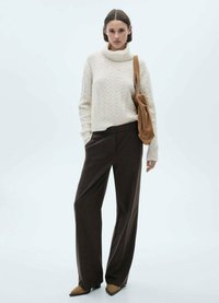 Crème kabelgebreide coltrui, bruine geruite broek en tan suede enkellaarsjes met hak. Bruine schoudertas met een geplooid ontwerp.
