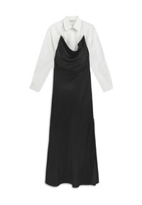 Vestido de satén negro tipo slip sobre una camisa blanca de botones, con un escote drapeado, mangas largas y una textura suave.