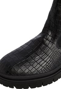 Stivale nero alla caviglia realizzato in materiale sintetico texturizzato, con un motivo in rilievo a croco e una suola in gomma spessa e robusta.
