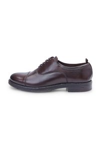 Chaussure de ville en cuir marron avec un bout arrondi, des détails de couture droits et courbes, un design à lacets et un talon empilé.