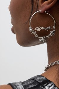 Pendiente de aro de plata con acentos florales y el texto "Ed Hardy", con detalles intrincados y una superficie suave y brillante.