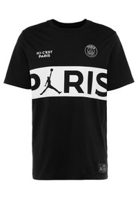 Camiseta de algodón negra con una franja horizontal blanca que lleva "PARIS" en letras en negrita, una silueta de Jordan y logotipos en el pecho y el dobladillo.