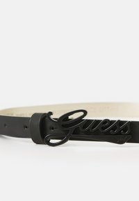 Zwarte synthetische riem met een glanzende zwarte logo-buckle. Heeft een soepele textuur en verstelbare gaten langs de band. Elegante designelementen.