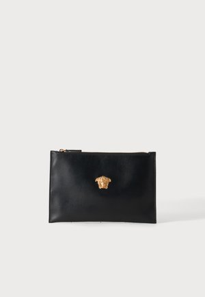 Bustina in pelle nera con zip e emblema dorato della testa di Medusa centrato sul davanti su sfondo bianco.