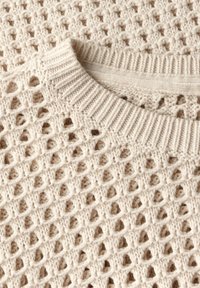 Strickpullover in Creme mit offenem Gittermuster. Verfügt über einen gerippten Rundhalsausschnitt und ein weiches, strukturiertes Garn. Leicht und atmungsaktiv im Design.