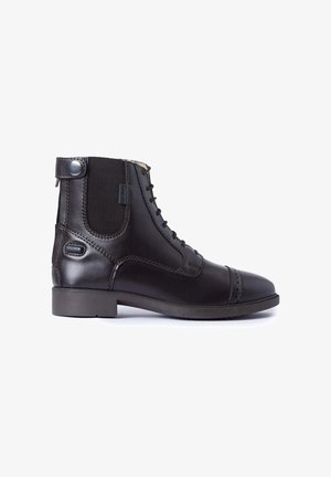 Stivaletto alla caviglia in pelle nera con lacci, pannello laterale elastico, dettagli brogue sulla punta e tacco basso impilato.