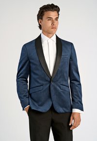 Marinblå, texturerad kavaj med svart satinrevers, en-knappsstängning, två framfickor och matchad med en vit skjorta.