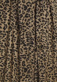 Luipaardprintstof met donkerbruine en zwarte patronen op een beige achtergrond met zichtbare plooien en plooiingen.