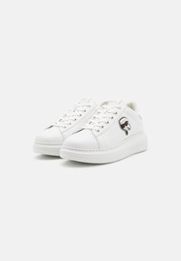 Baskets en cuir blanc avec bout rond, semelle plate et fermeture à lacets. Présentent un logo sur le côté et un détail de surpiqûre contrastante.