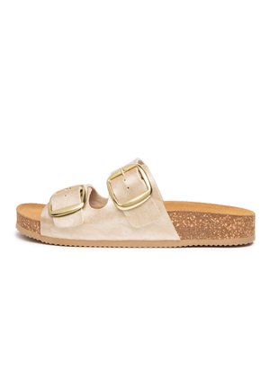 Sandalo beige slip-on con suola in sughero e due larghe fibbie dorate sulla parte superiore, piatto con suola esterna in gomma texturizzata.
