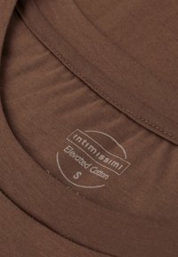 Collare di una maglietta in cotone marrone in primo piano, che mostra la texture liscia e i dettagli dell'etichetta: "Intimissimi Elevated Cotton", taglia S, caratteri bianchi.