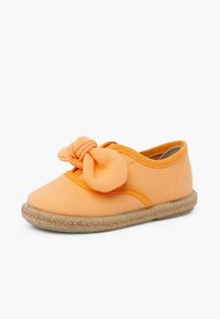 Scarpa di tela arancione con punta rotonda, caratterizzata da un grande fiocco e dettagli cuciti a texture. Suola in stile espadrilles avvolta in juta.
