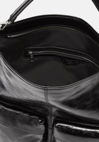 Czarna skórzana torba na ramię o błyszczącej powierzchni, z wewnętrzną kieszenią na zamek błyskawiczny i miękką podszewką. Zawiera podwójne uchwyty.