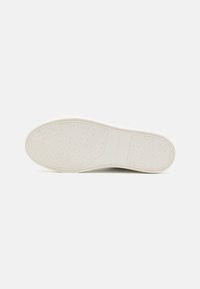 Suola di sneaker bianca con un motivo testurizzato e un sottile marchio. Il design presenta bordi arrotondati e un materiale in gomma flessibile.