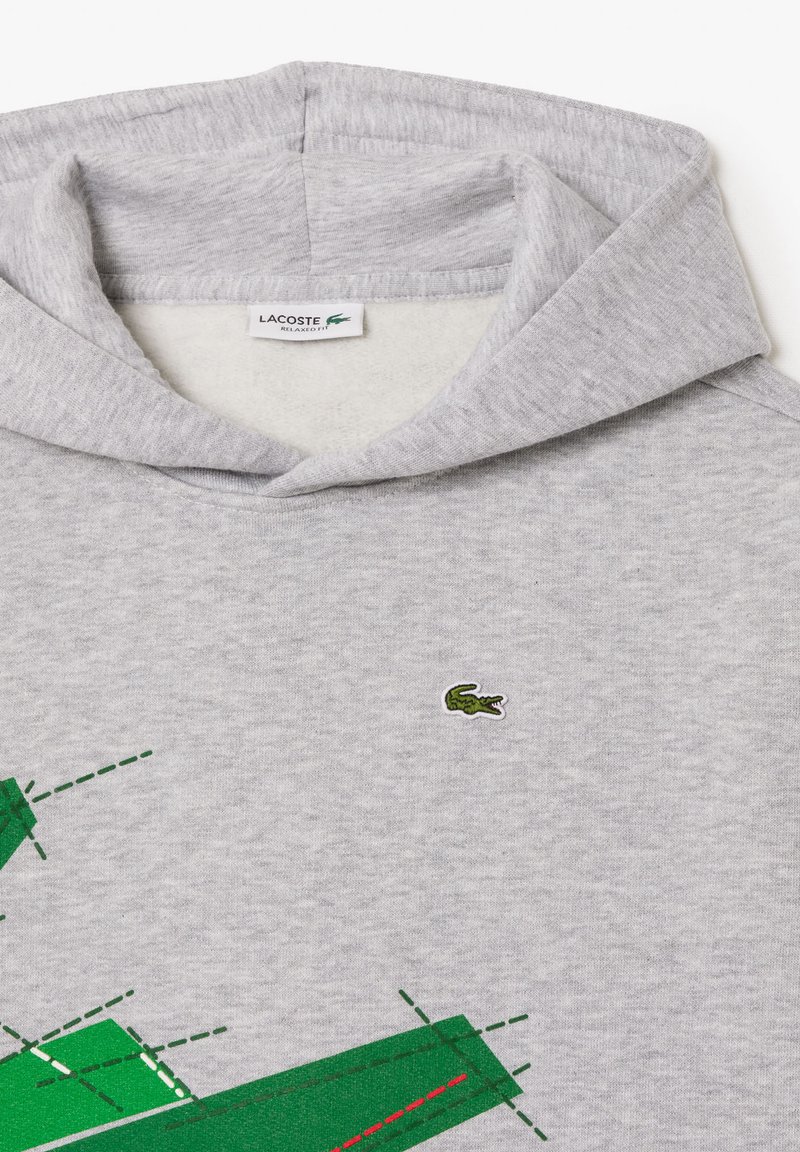 Grijze hoodie met een groen krokodil logo, met een grafisch ontwerp in groene en rode accenten. Zachte, geweven stof en een ontspannen pasvorm.