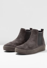 Tmavě šedé semišové kotníkové boty s elastickými bočními panely a ribbenou podrážkou, které mají elegantní, zaoblený design špičky.
