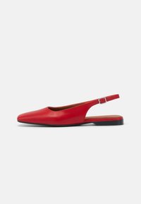 Chaussure slingback en cuir rouge avec un bout pointu, un talon ouvert et une semelle noire plate. Comprend une petite sangle réglable avec boucle.