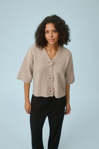 Bež kardigan s V-izrezom, kratkim rukavima i tri ukrasna gumba u obliku cvijeta. Tkanina pletena teksturom i detalj rebrastog poruba.