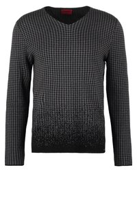 Pull en tricot à col en V avec un motif pied-de-poule noir et gris et un effet dégradé s'estompant en noir uni en bas. Manches longues.