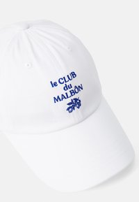 White cotton baseball cap with navy blue embroidered text "le CLUB du MALBÔN" and leaf design. Six-panel construction and curved brim.