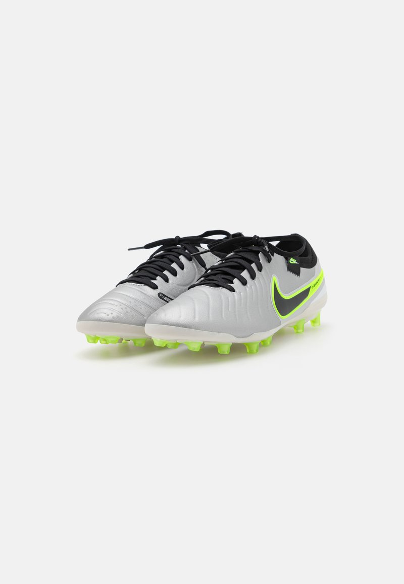Des crampons de football avec un schéma de couleurs argent et noir, dotés d'un matériau synthétique texturé, de lacets noirs et de crampons verts fluo.