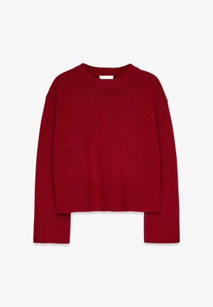 Punainen neulottu paita pyöreällä kaula-aukkolla, pudotetut olkapäät sekä resorit hihoissa ja helmassa. Kangas näyttää pehmeältä ja tekstuuriltaan.