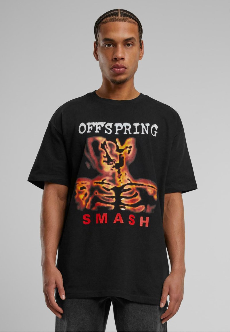 T-shirt noir surdimensionné présentant un graphique central d'un squelette en flammes, avec le texte "OFFSPRING" au-dessus et "SMASH" en rouge en dessous.