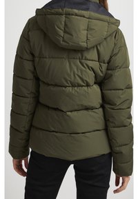 Olivgrön vadderad jacka med svart huva, med quiltade sektioner och en slät textur. Synliga sömmar framhäver dess strukturerade design.