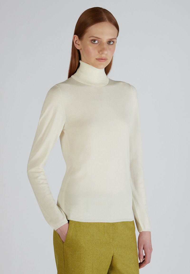 Crème coltrui gemaakt van een zachte stof, met lange mouwen en een aansluitend ontwerp. Gepaard met gestructureerde olijfgroene broek.