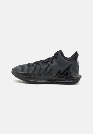 Baskets de sport noires avec empeigne en mesh, semelle rembourrée et grand logo Nike brillant sur le côté.
