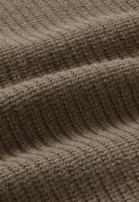 Tissu tricoté marron texturé avec des motifs en relief et une finition douce et duveteuse. Le matériau semble épais et chaud, idéal pour des vêtements confortables.