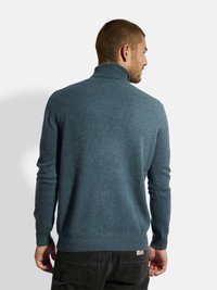 Blauer Strickpullover mit hohem Kragen und langen Ärmeln, aus weichem Material gefertigt. Verfügt über einen taillierten Saum und minimale Nähte für einen klaren Look.