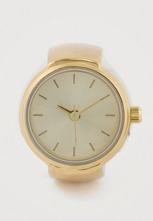 Montre analogique ton or avec un boîtier rond, un cadran minimaliste et des index horaires droits. Fini lisse et brillant avec une surface de cadran texturée.