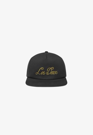 Casquette noire en textile avec une visière plate. Présente une broderie en or cursif sur le devant avec l'inscription "Les Deux". Design simple, sans accents supplémentaires.