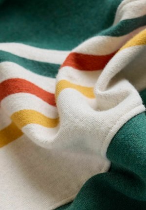 Úpletová tkanina s pruhy v zelené, krémové, oranžové a žluté barvě. Texturovaný povrch s měkkým, hebkým vzhledem a jemným splýváním.