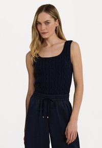 Débardeur en tricot bleu marine avec un décolleté carré et une texture en tricot torsadé, associé à un pantalon foncé à cordon de serrage.