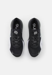 Mustat urheilukengät, joissa on verkkomateriaali, teksturoidut yksityiskohdat, valkoiset Nike-logoswooshit, pyöreät nauhat ja pehmustettu pohja.