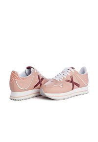 Scarpe sportive rosa con texture perforata, accenti bordeaux a contrasto, lacci bianchi e una suola spessa bianca.