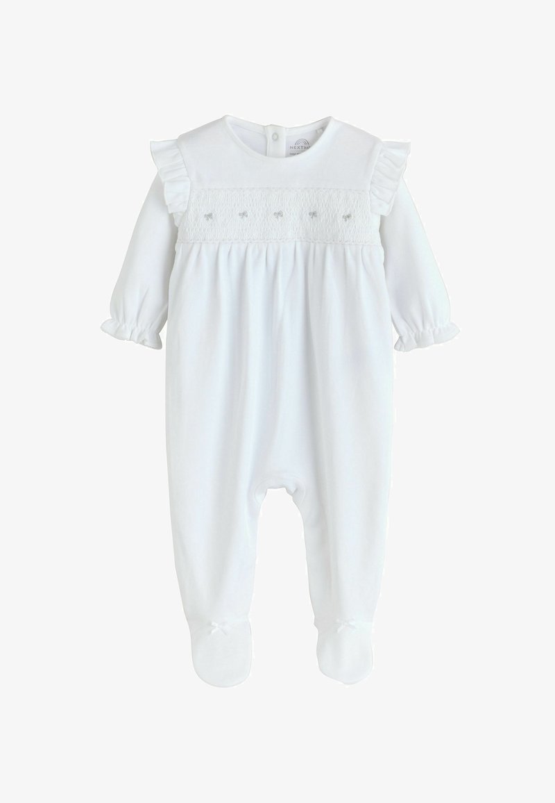 Combinaison blanche pour bébé à manches longues avec épaules volantées, détail brodé sur la poitrine, poignets froncés et pieds fermés avec petits nœuds.
