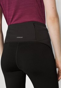 Czarne legginsy AEROREADY z wysokim stanem, z małą kieszonką na zamek oraz gładkim, elastycznym materiałem zapewniającym komfort i swobodę ruchów.