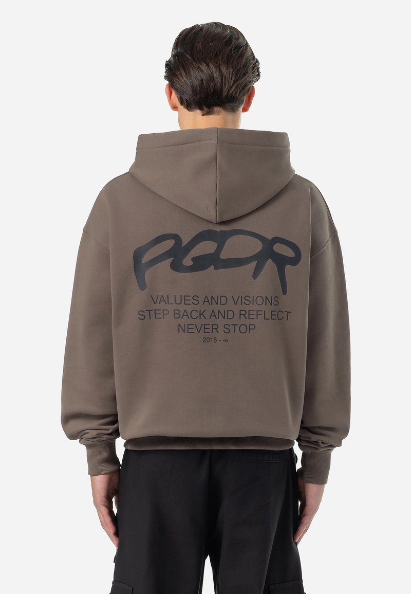 Sudadera marrón con una textura suave, presenta un gran gráfico negro en la espalda con texto y un logotipo en cursiva, terminado con capucha ajustable.