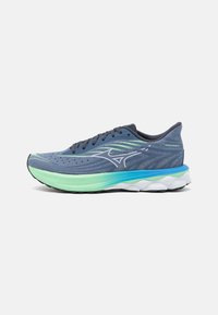 Zapatilla de running para hombre con parte superior azul, entresuela en degradado verde, suela blanca y detalles reflectantes. Construcción de malla ligera.