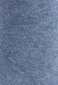 Calzino blu lavorato a maglia con un motivo testurizzato, caratterizzato da una combinazione di sfumature di blu più chiare e più scure per un effetto di profondità. Finitura del materiale liscia.