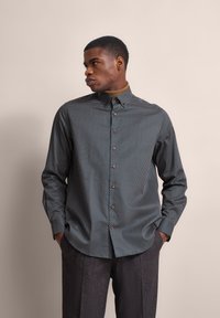 Langärmliges Hemd mit Knopfleiste in Marineblau mit weißen Punkten, mit abgerundetem Saum, Spread-Kragen und kontrastierenden Knöpfen.