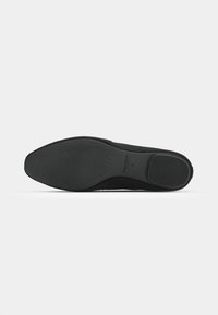 Must mustriga mustad jalatsid, sujuva viimistluse ja tekstuuriga mustriga, ümarate varvastega disainiga. Minimalistlik varustus ja õhuke konts.